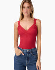 Woman wearing a red lace tank top and blue jeans on a white background