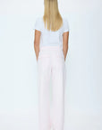 Person wearing a white t-shirt and light pink wide-leg pants on a white background