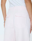 Person wearing light pink pants with a white background