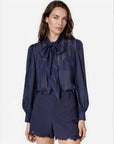 model wearing a navy sheer top with a tie neck with navy shorts that lace a small lace trim on a white background