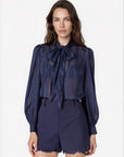 model wearing a navy sheer top with a tie neck with navy shorts that lace a small lace trim on a white background