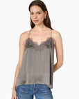 model wearing a gunmetal colored cami with a lace trim and blue jeans on a white background