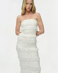 Woman wearing a strapless, layered white dress on a plain background