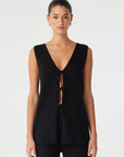 Woman wearing a black sleeveless top with a deep neckline on a white background