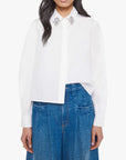 Woman wearing a white blouse with embellishments and blue jeans on a white background