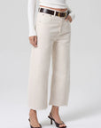 Person wearing white jeans with a black belt on a white background