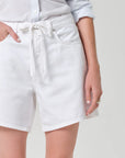 White denim shorts worn by a person on a plain background