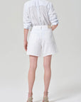 Person wearing a white shirt and white shorts on a plain background