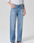 Person wearing light blue jeans and a white shirt on a plain background
