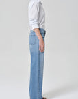 Person wearing light blue jeans and a white shirt on a plain background