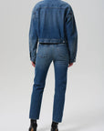 Person wearing a blue denim jacket and jeans on a white background back view