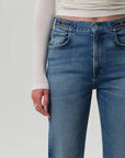 Blue jeans worn by a person on a plain background detail view