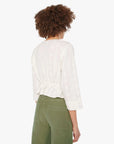 Person wearing a white blouse and green pants on a white background, back