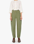 Woman wearing a white blouse and green pants on a white background, full body front