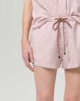 Person wearing a pink and white striped set with a tie waist on a light gray background