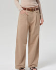 Person wearing beige wide-leg pants with a brown belt on a white background