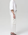 Person wearing a white outfit with cargo pants on a plain background
