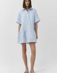 Woman wearing a light blue and white striped dress on a white background