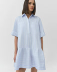 Woman wearing a light blue and white striped dress on a plain background