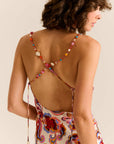 Woman wearing a colorful dress with a beaded back detail on a beige background