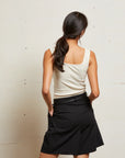Woman wearing a white top and black skirt against a plain background back view