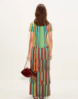 Woman wearing a colorful striped skirt holding a red handbag on a white background