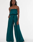 Woman wearing a teal strapless jumpsuit on a white background