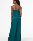 Woman wearing a teal strapless jumpsuit on a white background