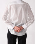 Person wearing a white shirt and black pants on a white background