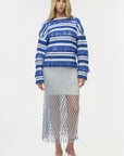 Woman wearing a blue and white striped sweater with a fishnet skirt on a white background