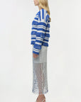 Woman wearing a blue and white striped sweater with a long, patterned skirt on a white background