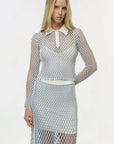 Woman wearing a fishnet outfit with a white collar on a plain background