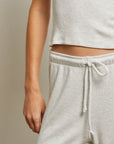 Person wearing light gray ribbed top and pants against a neutral background waistband view
