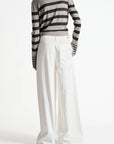 Person wearing a striped sweater and white pants on a white background