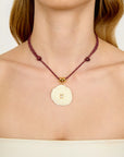 Necklace with a circular shell pendant featuring a square symbol on a plain background