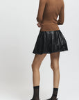 Person wearing a brown sweater and black skirt on a white background
