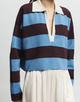 Person wearing a blue and brown striped shirt with a white collar on a plain background