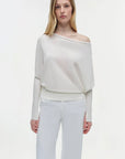 Woman wearing a white off-shoulder top and light gray pants on a white background