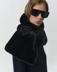 A model wearing a luxurious black fur collar with wide flared cuffs and black sunglasses, set against a plain light gray studio background.