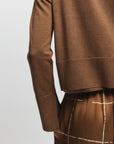 Brown long-sleeve top and pants on a light gray background, close up