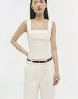 Woman wearing a white sleeveless top and pants on a white background