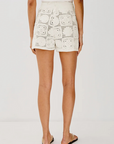 Person wearing white shorts with black pattern on a plain background, back view