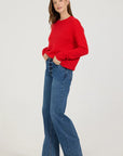 Woman wearing a red sweater and blue jeans on a white background