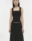 Woman wearing a black sleeveless top and long black skirt on a white background
