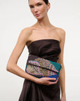 Woman holding a colorful beaded clutch against a plain background