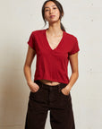 Person wearing a red top and dark pants against a plain background front view