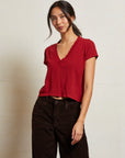 Woman wearing a red top and dark pants against a plain background front view