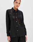 Woman wearing a black embroidered shirt and shorts on a white background front view