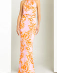 Woman wearing a pink and orange patterned halter neck dress against a white background