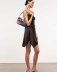 Woman wearing a brown strapless dress holding a patterned handbag on shoulder